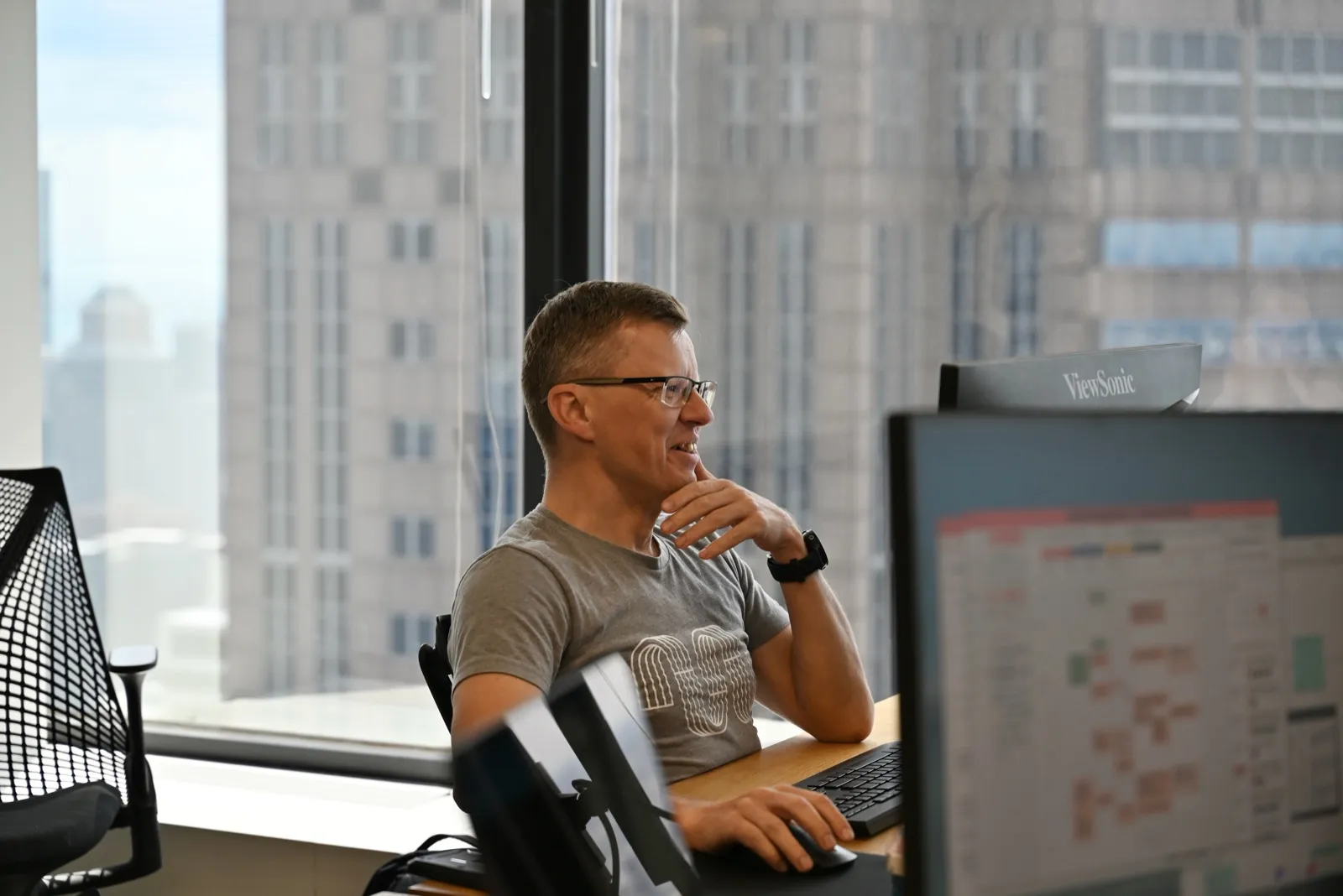 An engineer at a desk by a high-rise window, mid-conversation