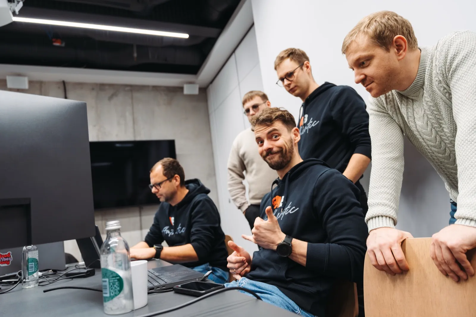 A hackathon huddle mugging for the camera around a monitor