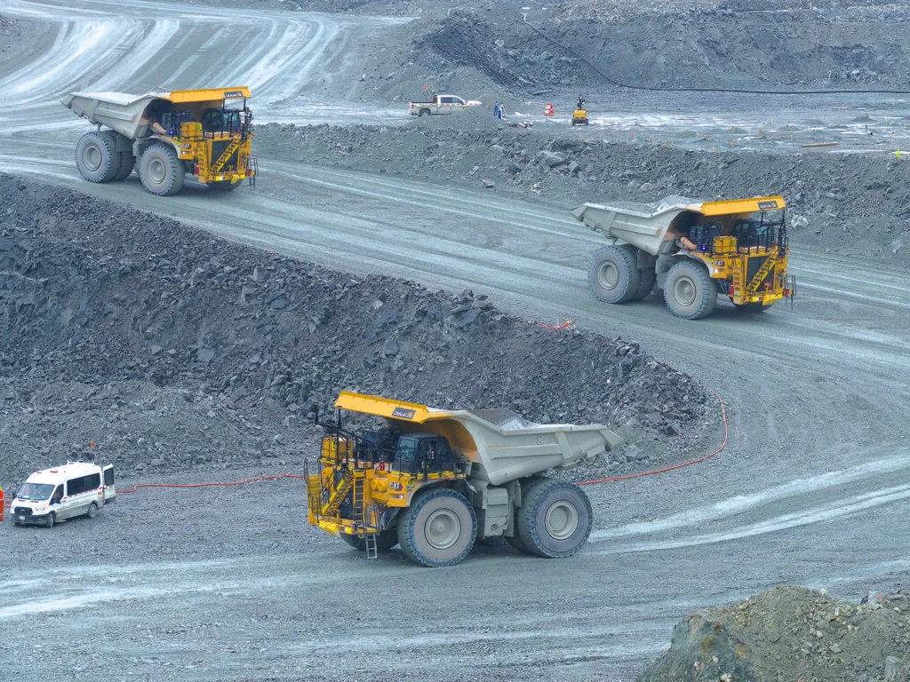 Autonomous haul trucks working a switchback road in an open-pit mine