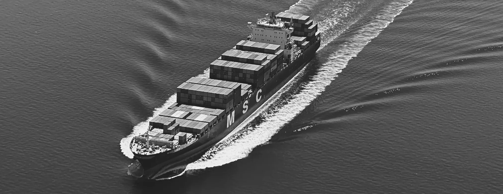 A container ship under way, seen from above with its wake trailing behind