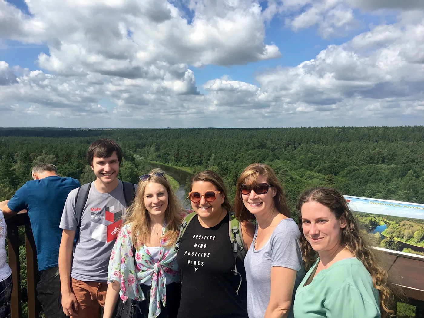 A group of people at a forest lookout tower overlooking the Lithuanian countryside