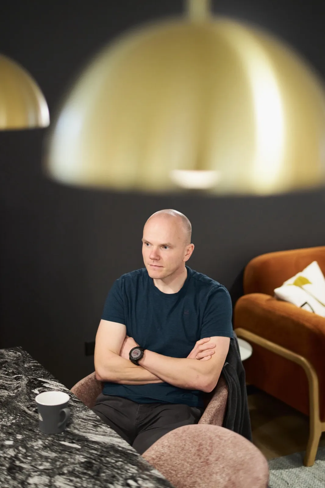 An engineer with a coffee at a marble table under brass pendant lamps