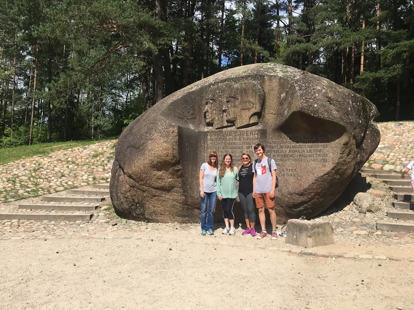 Four people standing in front of the Puntukas boulder near Anykščiai