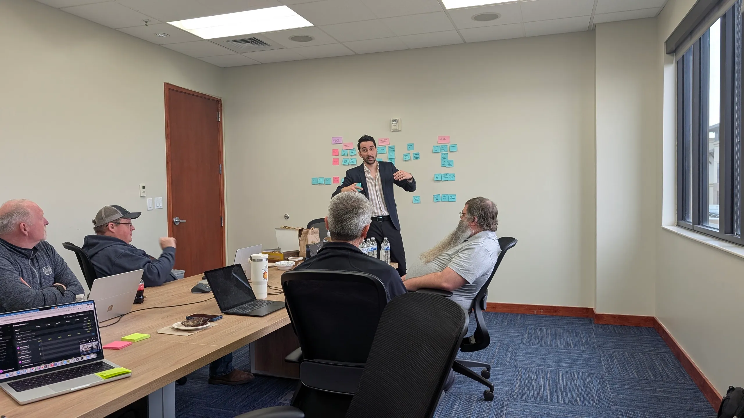 A workshop session at ASI: a facilitator at a wall of sticky notes in front of seated engineers
